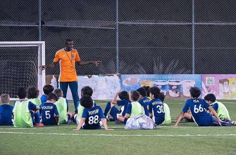 Young players and coaches standing together on a community pitch in Cameroon
