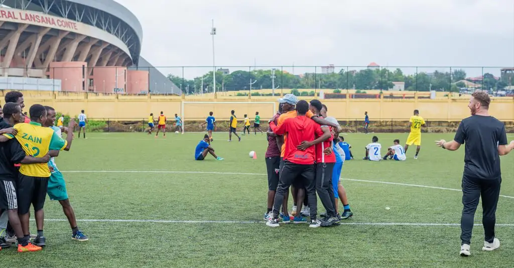 A coach presenting football tactics to a group of coaches and players during a seminar